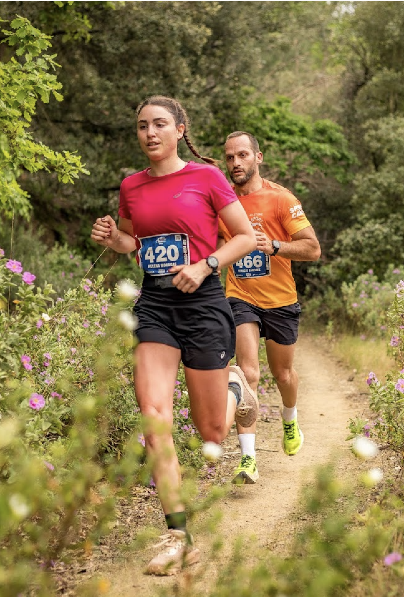 Pareja de corredores corriendo juntos entre flores de jara en Òrrius